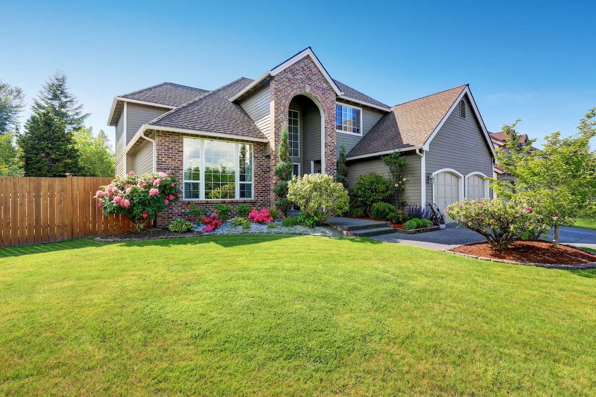 Luxury house exterior with brick and siding trim and double garage. Well kept garden around. Northwest, USA