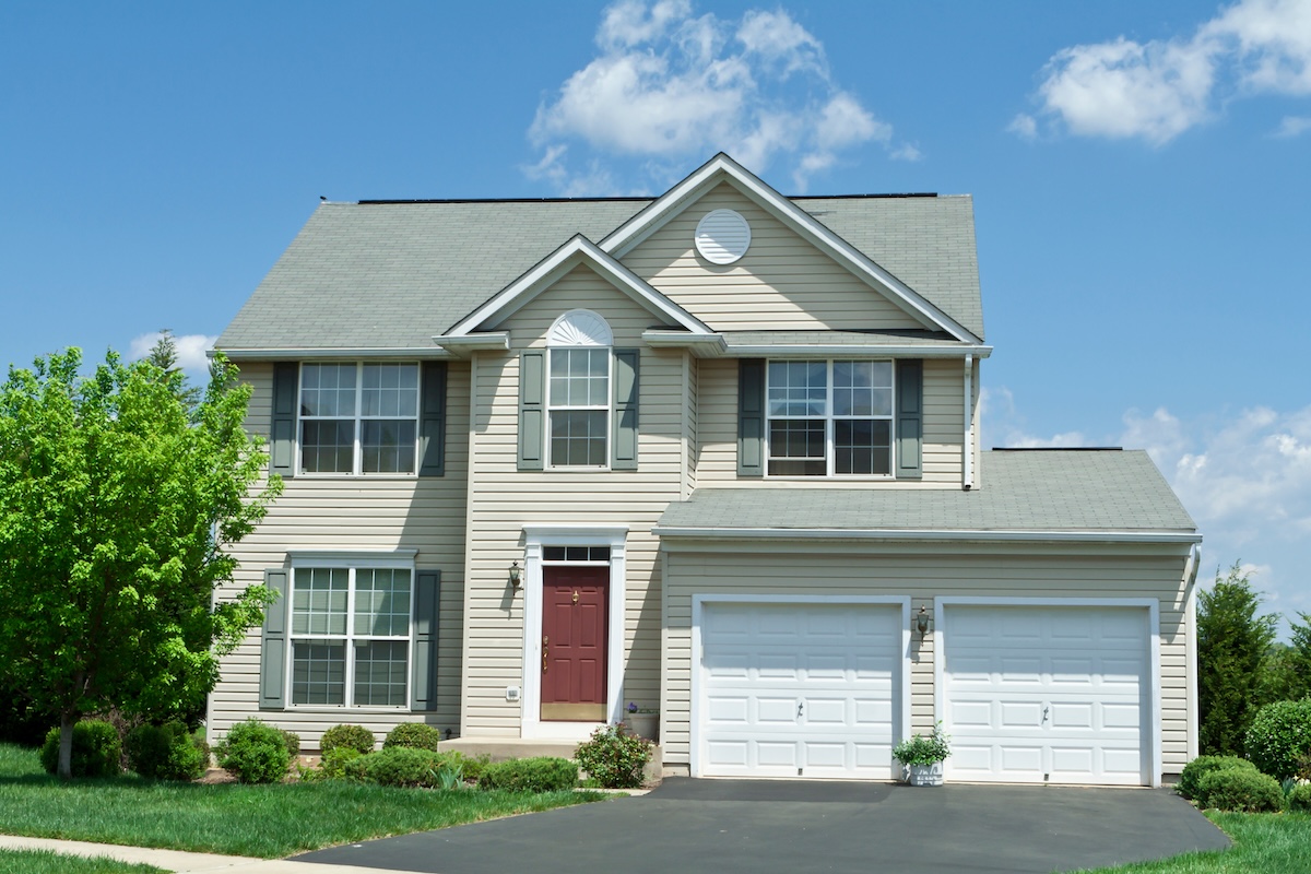 Modern vinyl sided single family home in suburban Maryland. House has two car garage, driveway and red door.