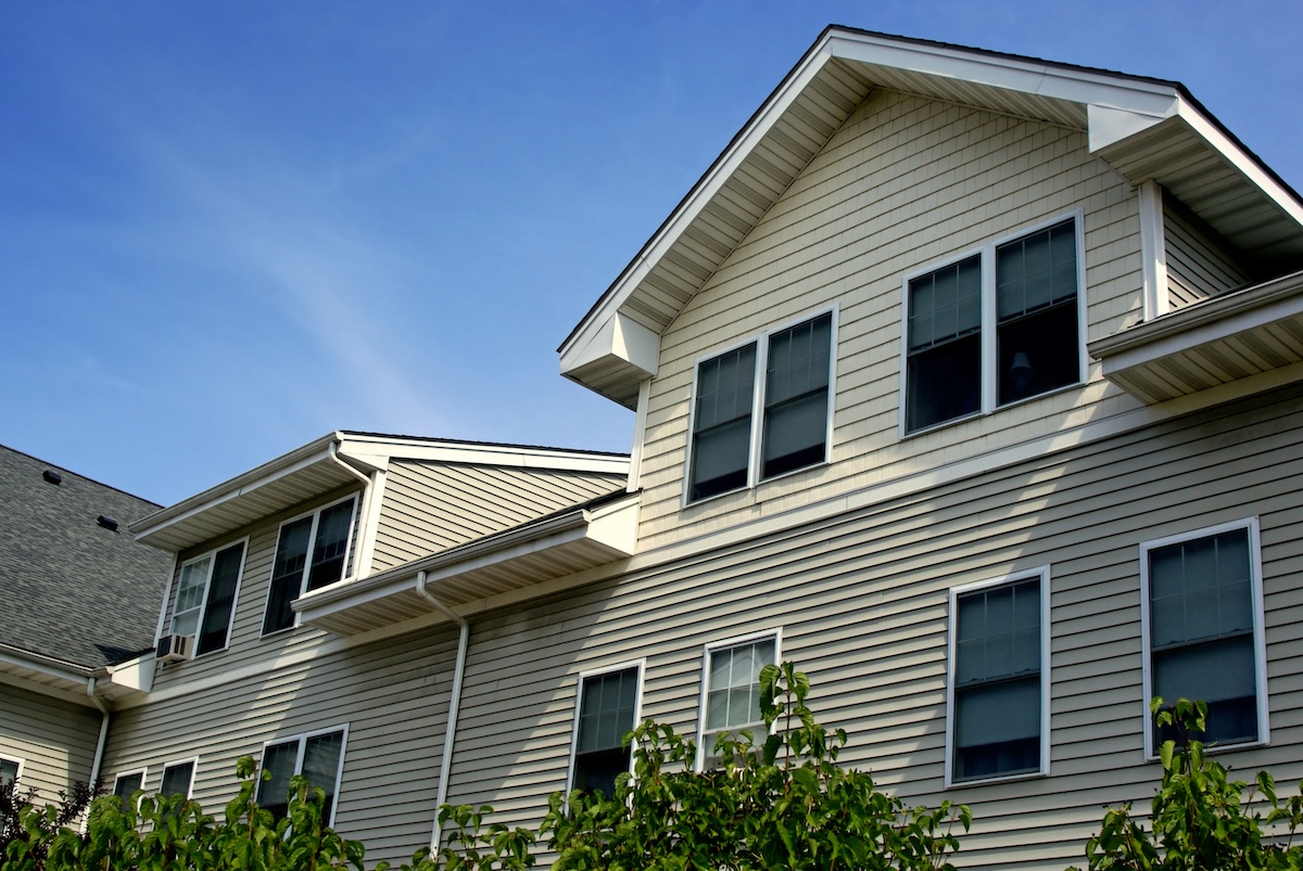 Vinyl sided condo building against a blue sky with wispy clouds