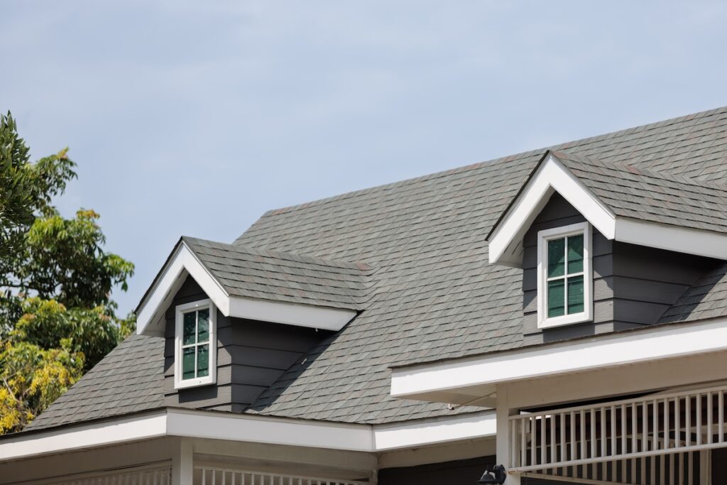 Roof shingles with garret house on top of the house. dark asphalt tiles on the roof background on afternoon time. dark asphalt tiles on the roof background gaf vs owens corning