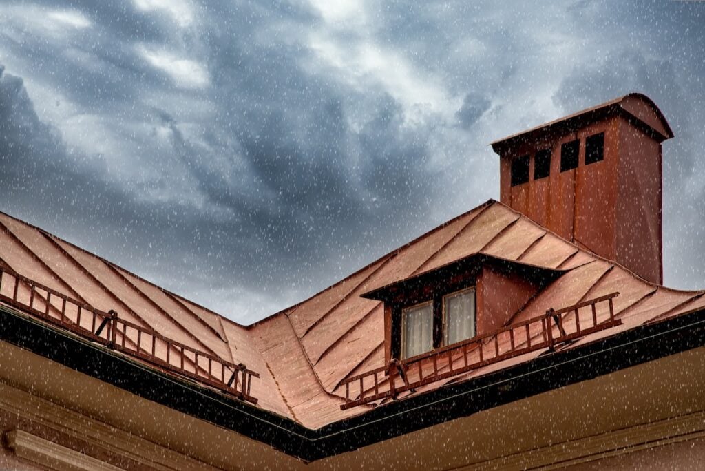 Close-up of a copper roof with dark cloudy sky and rain