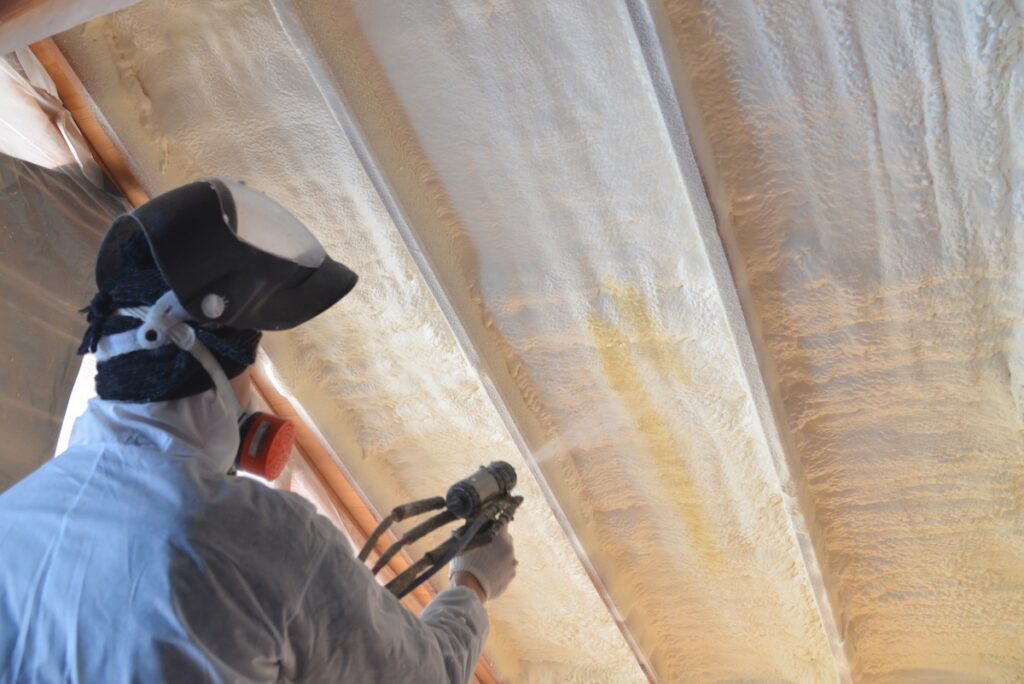 Polyurea Spraying, warming foam coating of roof, focus on wall.
