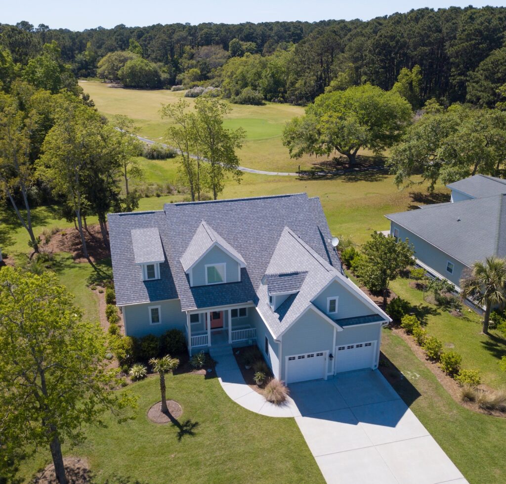 Low aerial view of house with new roof and golf course behind.