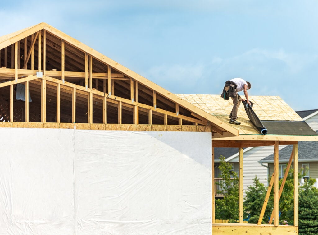 where does ice and water shield go on a roof  Worker installing underlayment sheet on wooden roof of new house. Renovation, improvement for exterior residential by professional builder. Durable build and construction business. Labor job concept